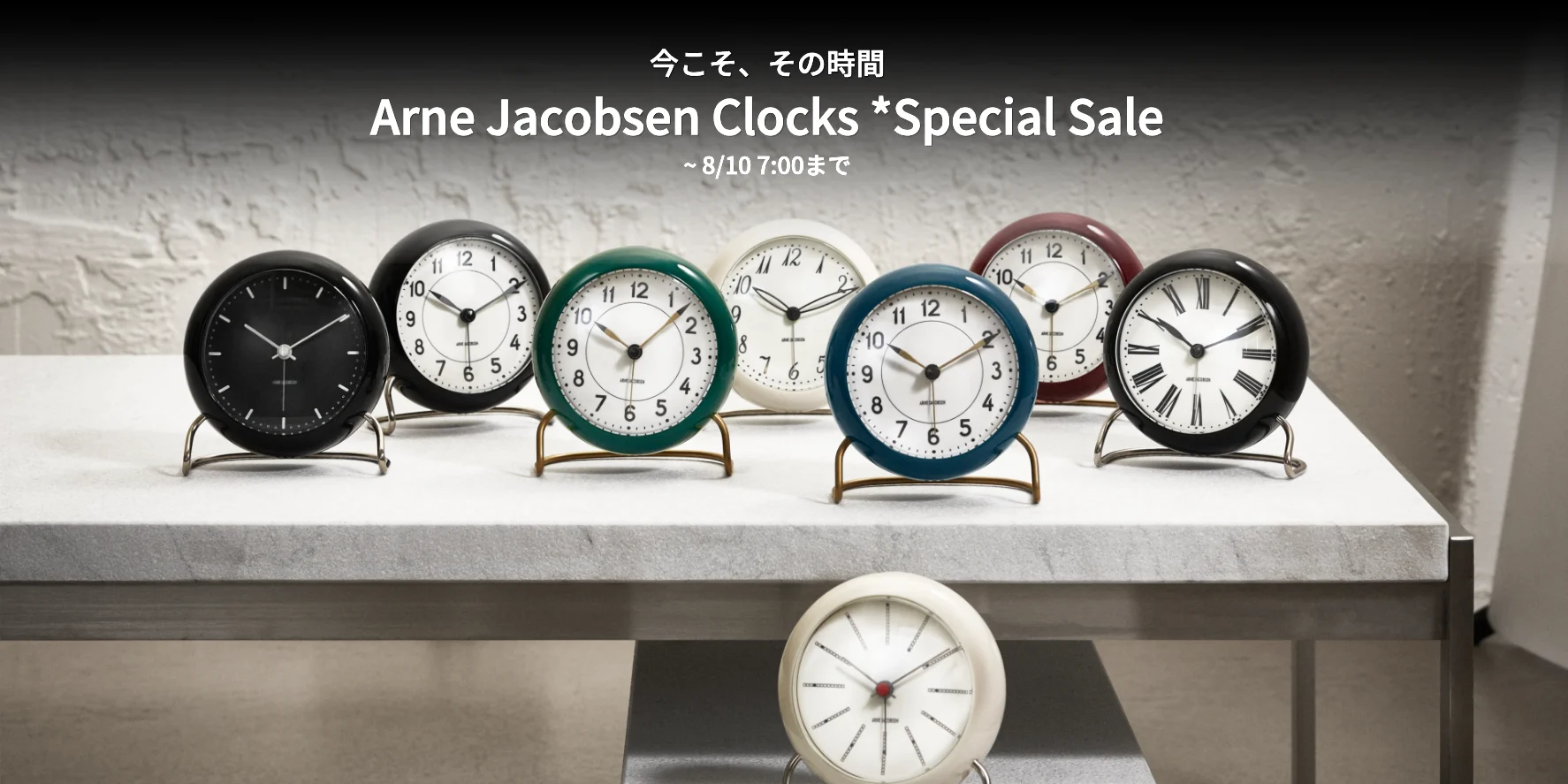 黒、白、緑、青、マルーンの丸い置時計8個。様々な文字盤デザインで、明るい表面に配置。