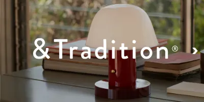&Traditionのロゴと、白いドーム型のシェードが付いた濃い赤色のテーブルランプの画像。